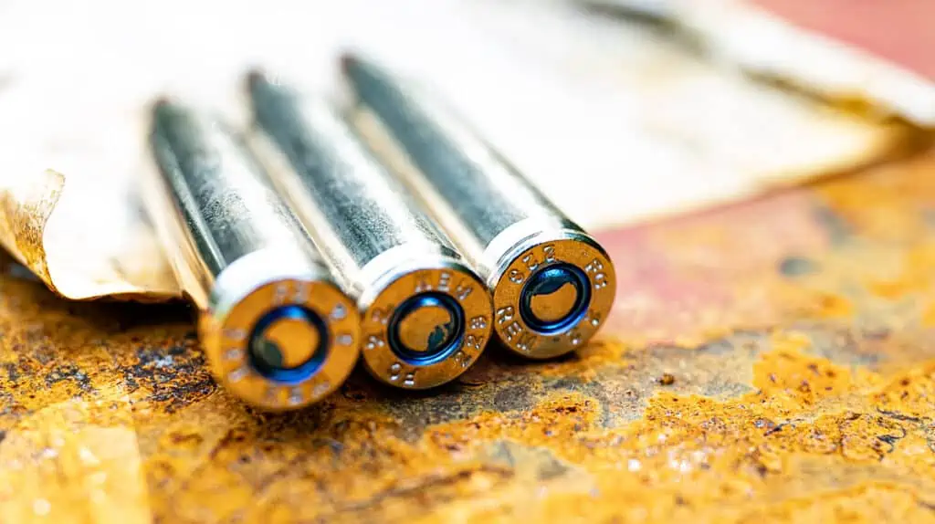 three 223 ammo cartridges on a barrel at a shooting range