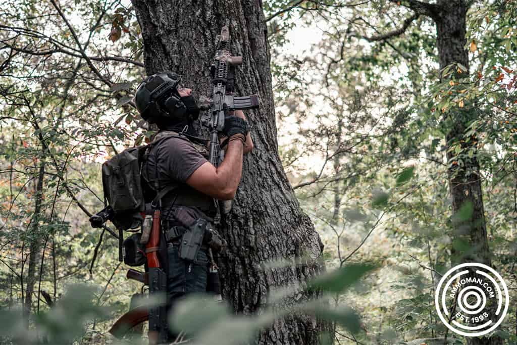 man standing against tree with a painted rifle