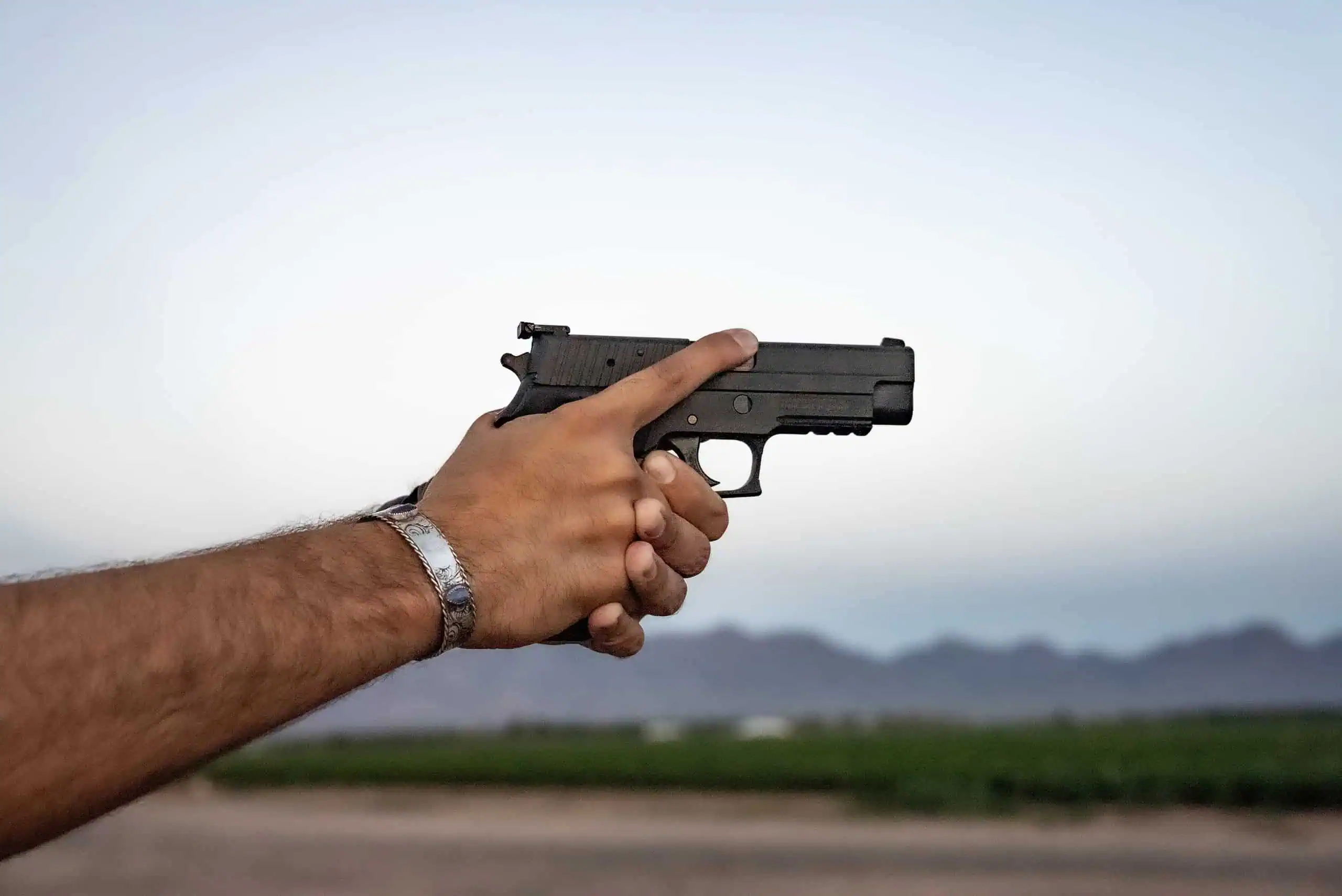 Man holding a pistol with his finger off of the rigger.