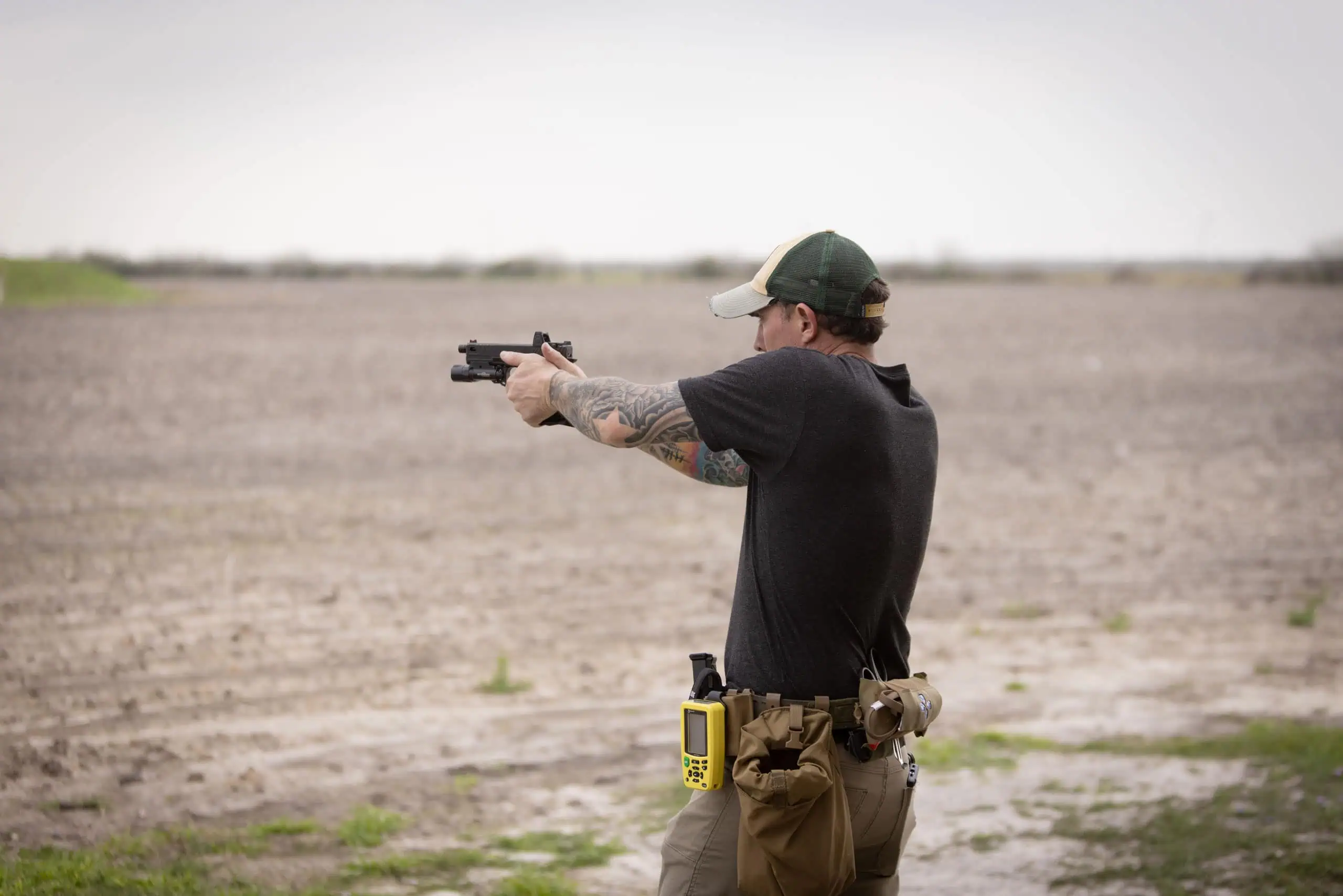 Man shooting pistol equipped with a red dot sight.