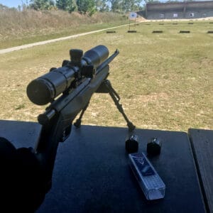 A rifle with an optic pointed down range as the author demonstrates rifle accuracy drills.